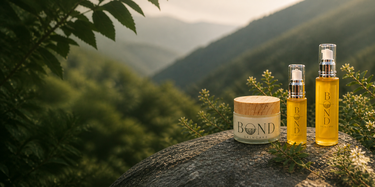 Bond Skincare cream jar and two golden oil bottles resting on a mossy stone, with a misty green mountain valley behind